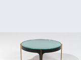 une table basse ronde en verre avec des pieds en laiton et un plateau en verre