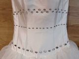 white wedding dress hanging on a hanger on a wooden floor