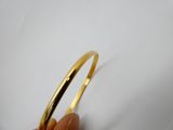 une main tenant un bracelet en or à maillons sur une surface blanche