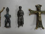 three metal figurines of a man and a cross