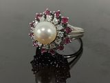 une photo d'une bague en perle et diamant posée sur un fond noir