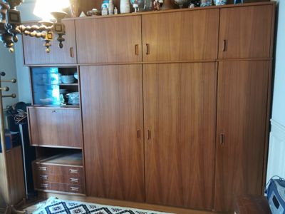 une armoire en bois dans un coin d'une pièce où se trouve un tapis noir et blanc au sol