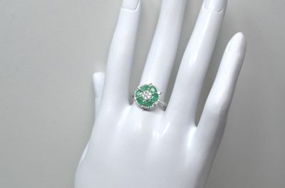 une image représentant la main d'une femme à laquelle est passée une bague verte et blanche