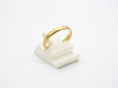 une image représentant une bague en or posée sur un bloc blanc