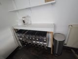 a wine rack in the corner of a room with a trash can