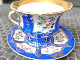 une tasse et une soucoupe posées sur une table où se trouve une bougie