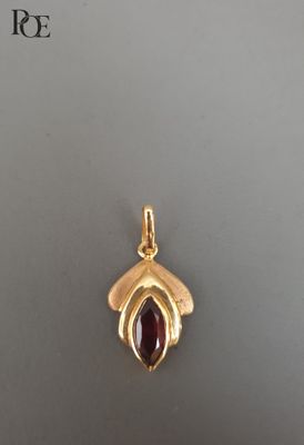 un gros plan d'un pendentif en or orné d'une pierre rouge