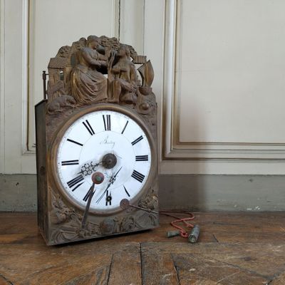 a clock that is sitting on the floor next to a wall