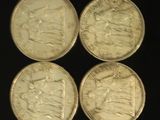four british silver coins sitting on top of a black surface