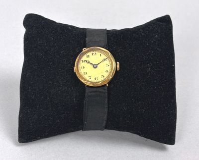 a small black pillow with a yellow watch on it
