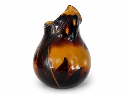 un vase brun et noir posé sur une surface blanche