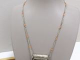a silver necklace with orange beads on a mannequin display
