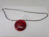un gros plan d'un pendentif en verre rouge suspendu à une chaîne en argent