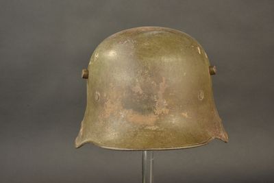 an old helmet on a metal stand against a gray background