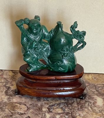 une statue verte représentant deux personnes assises sur un socle en bois
