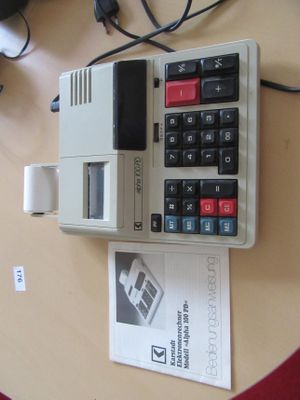 une calculatrice posée sur une table à côté d'un livre