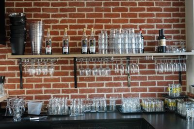 un mur de briques derrière le bar, avec des verres à vin sur les étagères