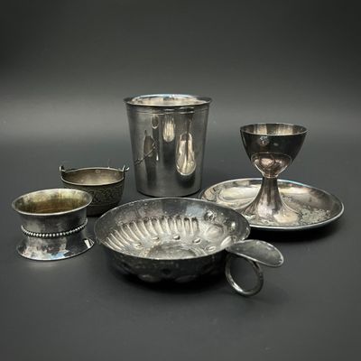 plusieurs plats et tasses en argent posés sur une table devant un fond noir