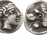 a silver coin with a head of a bull and a face of a woman