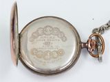 an old pocket watch with a chain on a white surface