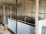 a room with a lot of stalls and a cow in it