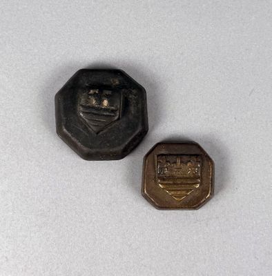 two small metal buttons sitting on top of a white surface