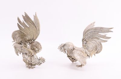 paire de figurines de coqs plaquées argent sur fond blanc