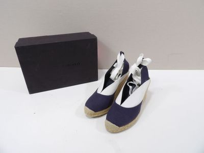 une paire de chaussures bleues et blanches posée à côté d'une boîte sur une surface blanche