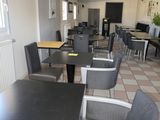 Des tables et des chaises sont alignées dans une pièce au sol carrelé.