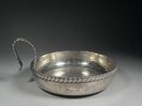 a silver bowl with a rope handle on a white surface
