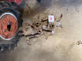 a red tractor with a rusted tire next to a pile of old tools