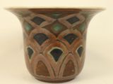 a brown and green vase sitting on a white surface