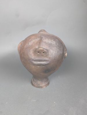 un vase marron orné d'un visage, posé sur une table