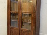 un meuble en bois avec des portes en verre dans le coin d'une pièce