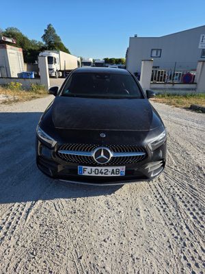 une voiture noire garée sur un chemin de terre devant un bâtiment