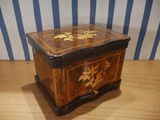 a small wooden box on a table with a striped wall behind it