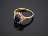 a gold ring with a sapphire and diamonds on a black surface