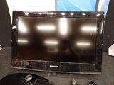 a flat screen tv sitting on top of a table next to a remote