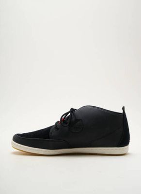la chaussure noire repose sur une surface blanche, sur fond blanc