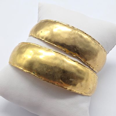 two gold plated rings on a white napkin on a white surface
