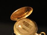 a gold pocket watch sitting on a black surface