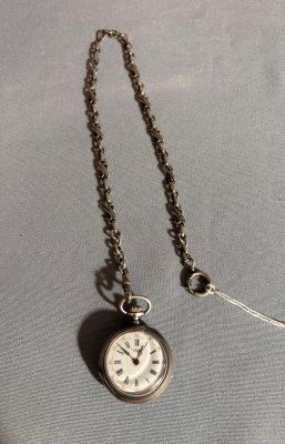 une vieille montre de poche à laquelle est accrochée une chaîne sur le côté