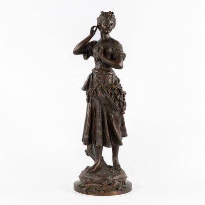 une statue en bronze représentant une femme tenant une fleur à la main