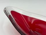 a red and white glass bowl on a white table