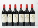 six bouteilles de vin rouge sont alignées sur une surface blanche
