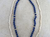 un collier de perles blanches et bleues posé sur une surface en marbre