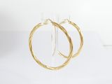 a pair of gold hoop earrings sitting on top of a clear stand