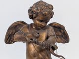 bronze statue of a little angel holding a bird on a white background