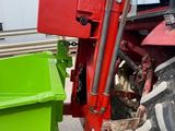a red tractor with a green bin in front of it