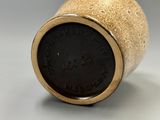 a gold vase with a black lid sitting on a table